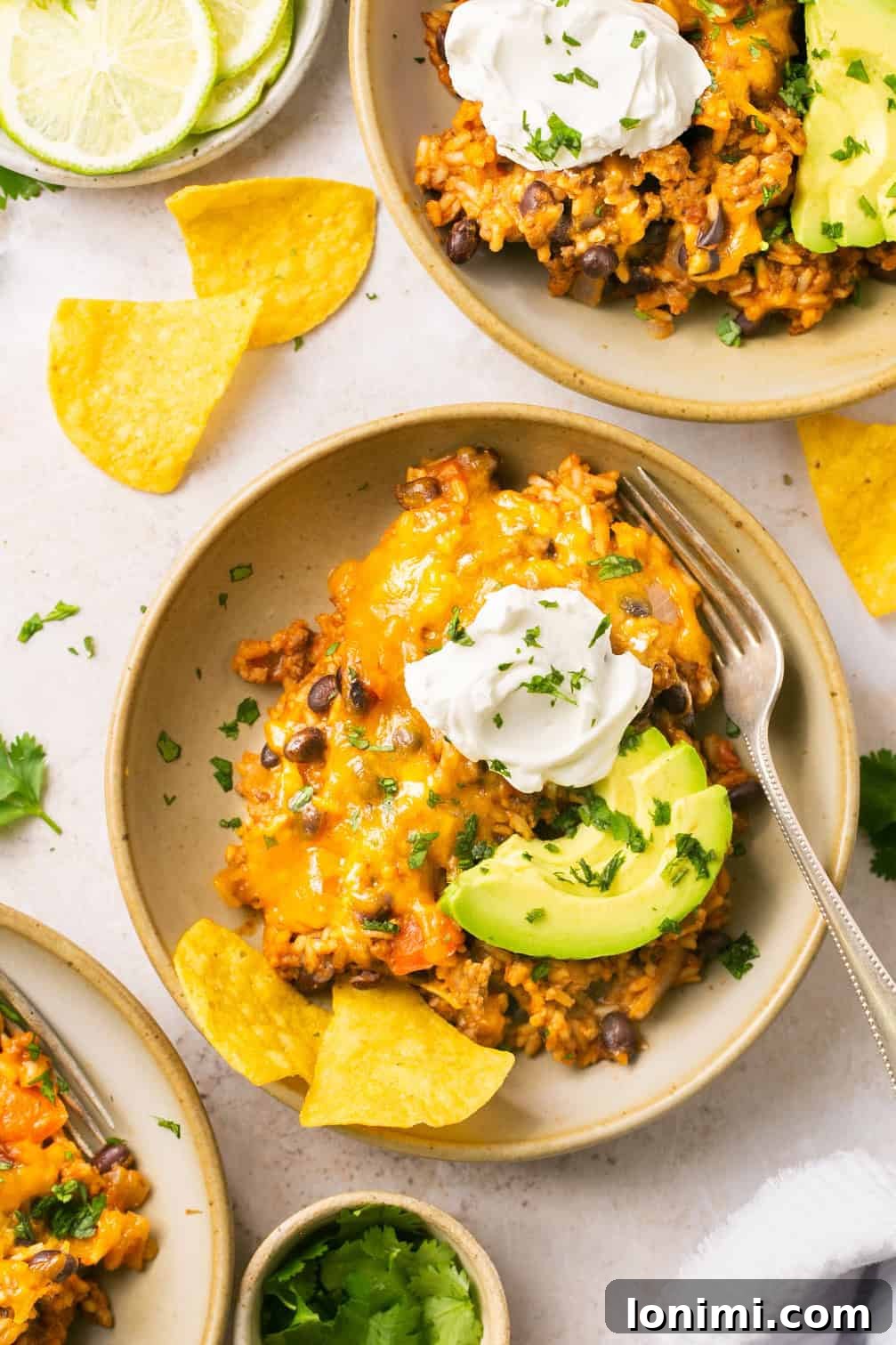 Two bowls of flavorful beef taco in a bowl recipe generously topped with creamy sour cream, fresh avocado slices, and vibrant cilantro sprigs, showcasing a perfect shell-less taco meal.