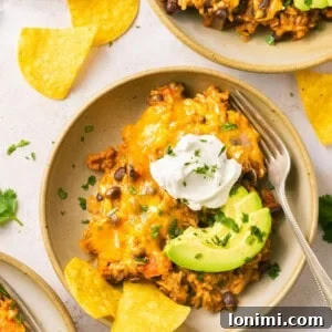 Loaded taco skillet in a bowl with sour cream, avocado, and chips