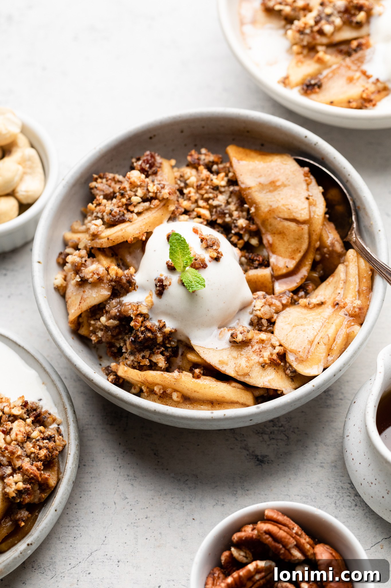A bowl of Paleo Apple Crisp topped with dairy-free vanilla ice cream and fresh mint, ready to eat.