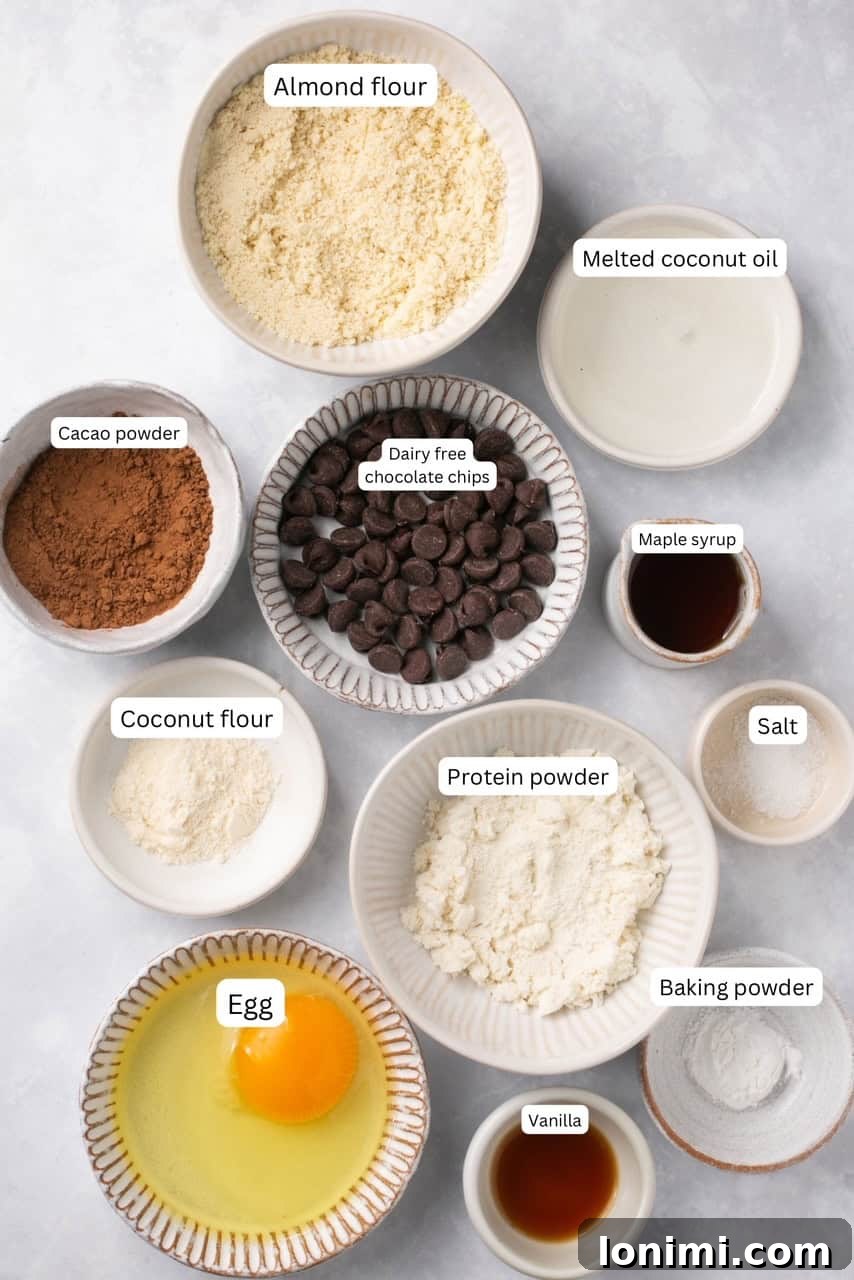 Arrangement of essential ingredients for a protein mug cake in nesting bowls, clearly labeled for easy identification.