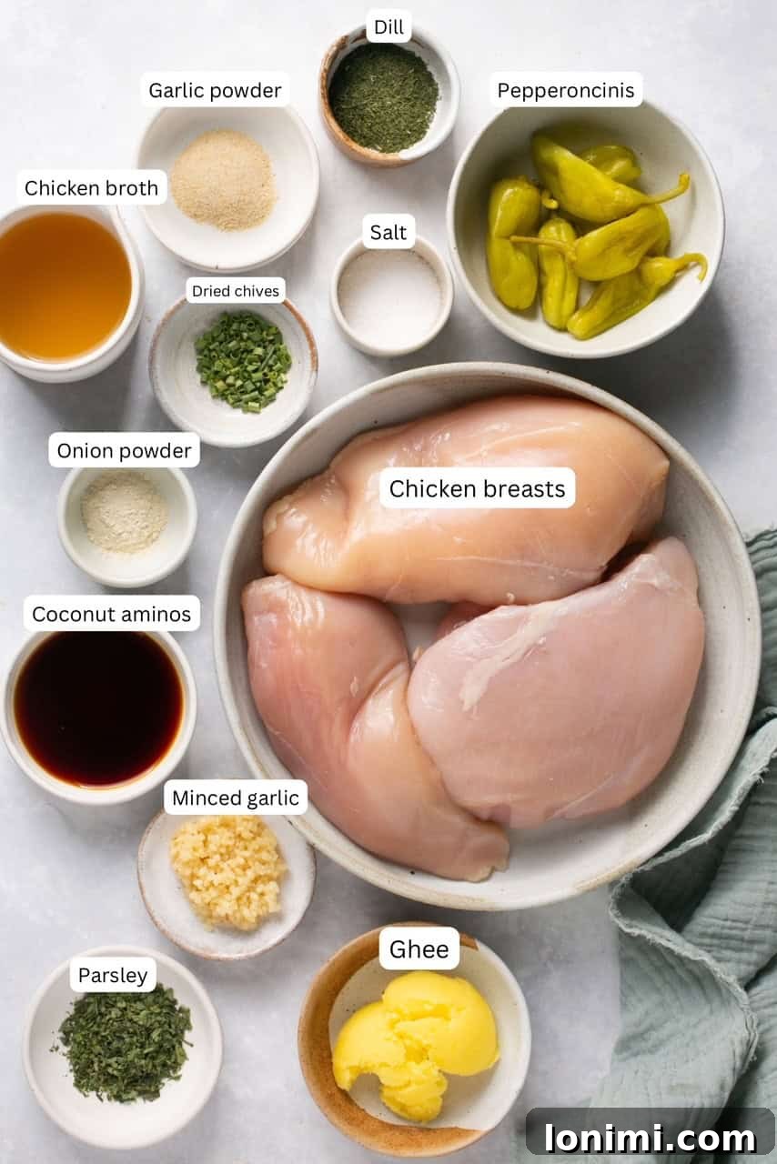 A collection of fresh ingredients for Mississippi Chicken, including chicken breasts, herbs, garlic, peppers, and ghee, neatly arranged in nesting bowls.