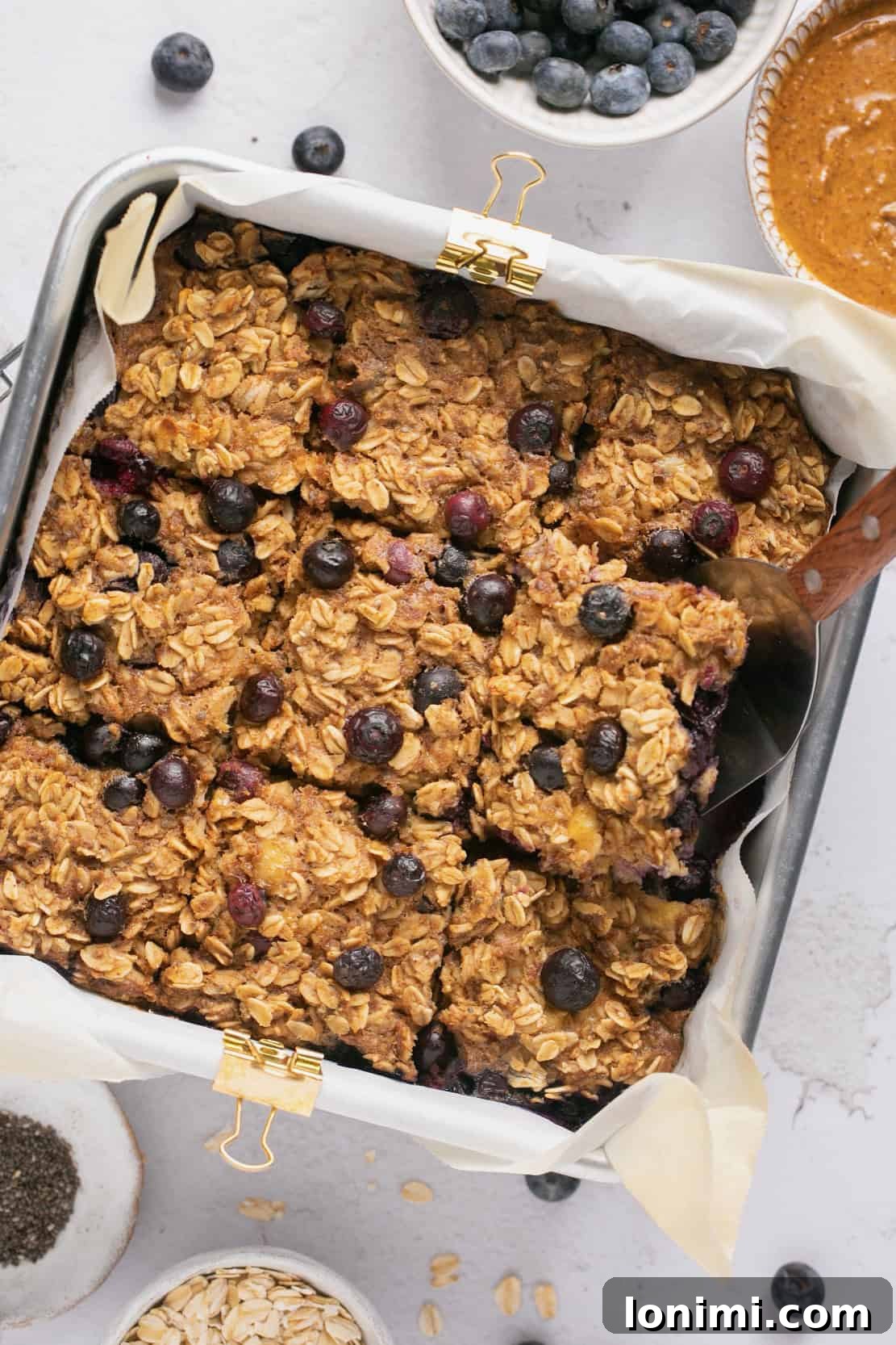 Protein-Packed Vegan Baked Oats 6 vegan baked oats in a baking dish topped with blueberries and cut into squares