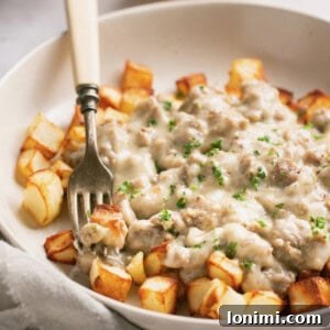 Keto and paleo sausage gravy over air fryer potatoes in a white bowl