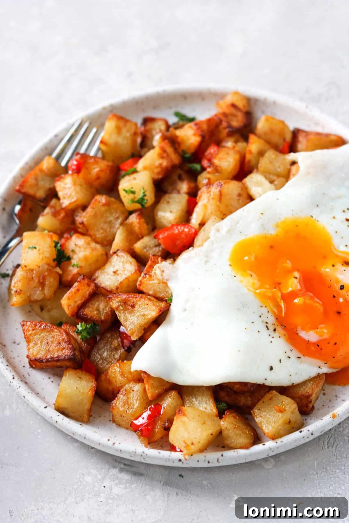 A sunny-side-up egg resting on a bed of air fryer breakfast potatoes.