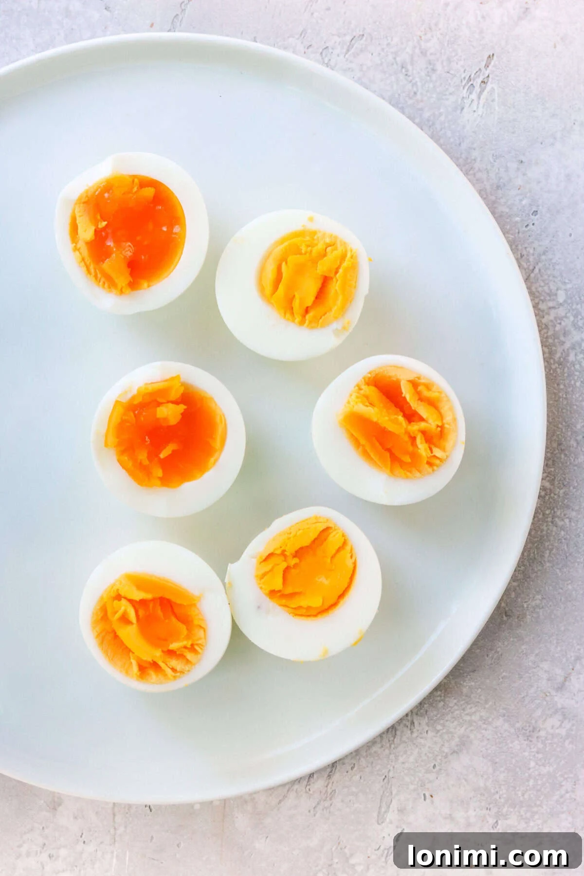 6 sliced hard-boiled eggs on a white plate, showcasing perfect doneness.