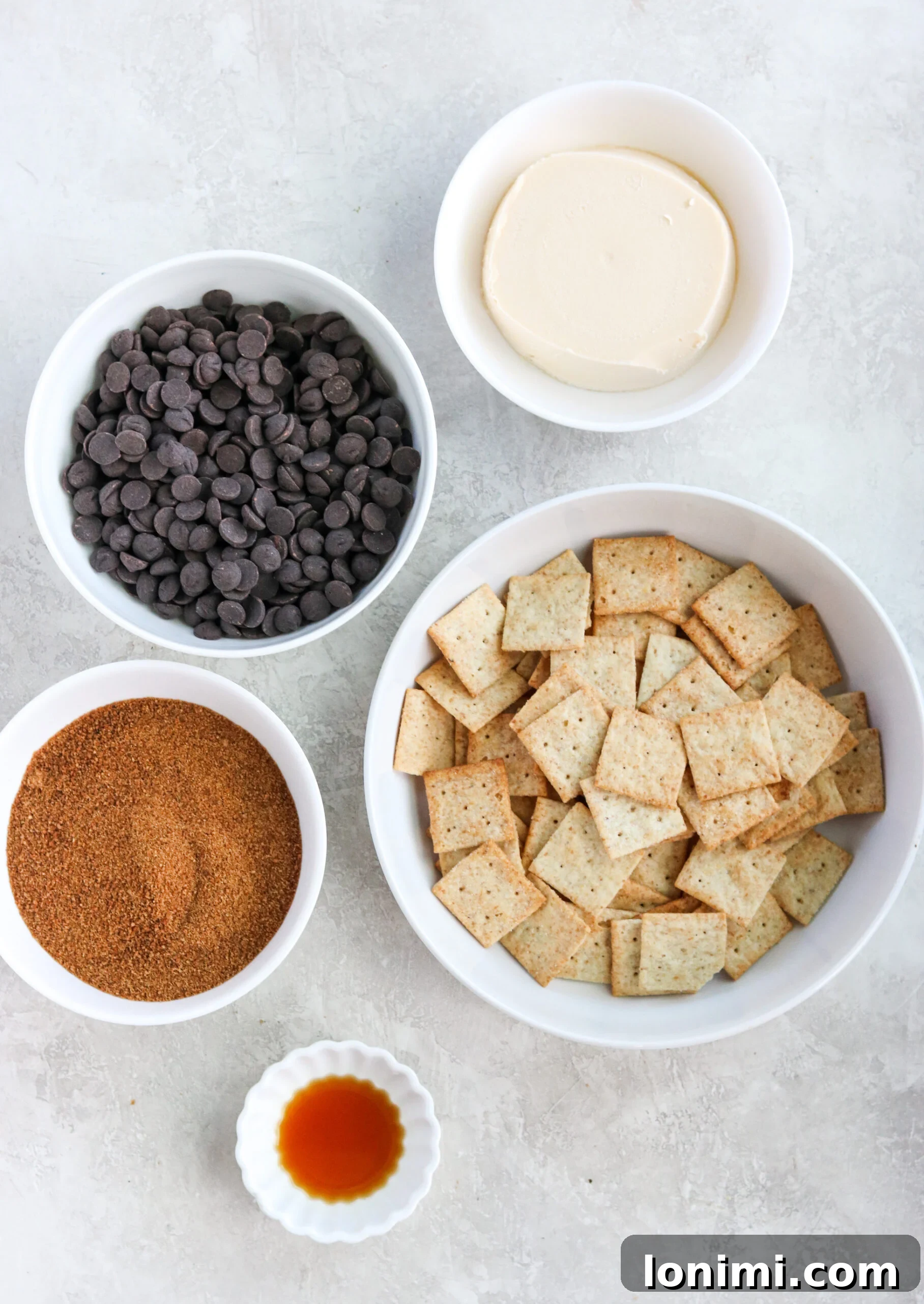 Bowls of essential ingredients for making Paleo Christmas Crack: almond flour crackers, dark chocolate chips, coconut sugar, butter, and vanilla extract.