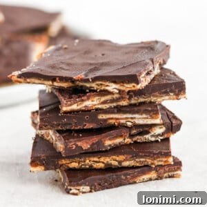 A stack of golden Christmas Crack dessert bars, showing the distinct layers of cracker, caramel, and chocolate.