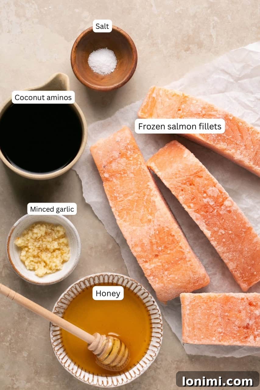 recipe ingredients in small bowls and labeled, including frozen salmon, garlic, honey, coconut aminos, and salt