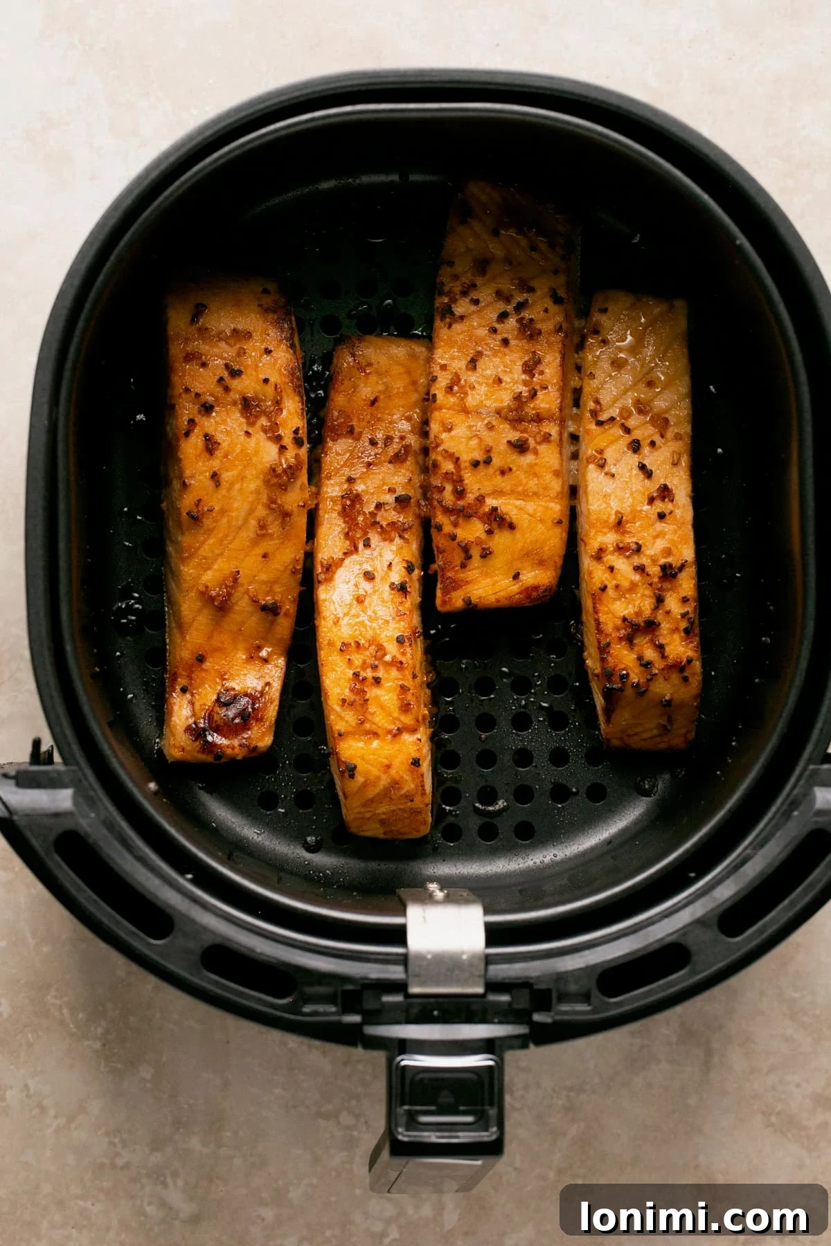 four salmon fillets in an air fryer basket.