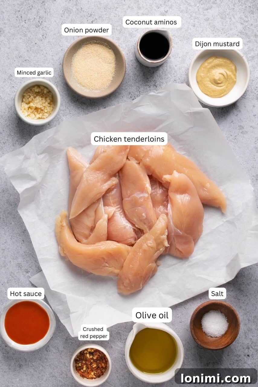 Crispy Air Fryer Naked Chicken Tenders 3 Individual bowls of ingredients for air fryer chicken tenderloins, labeled for easy prep and chicken tenderloins on parchment paper.