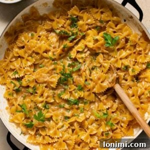 French Onion Pasta in a skillet topped with parsley with a serving spoon