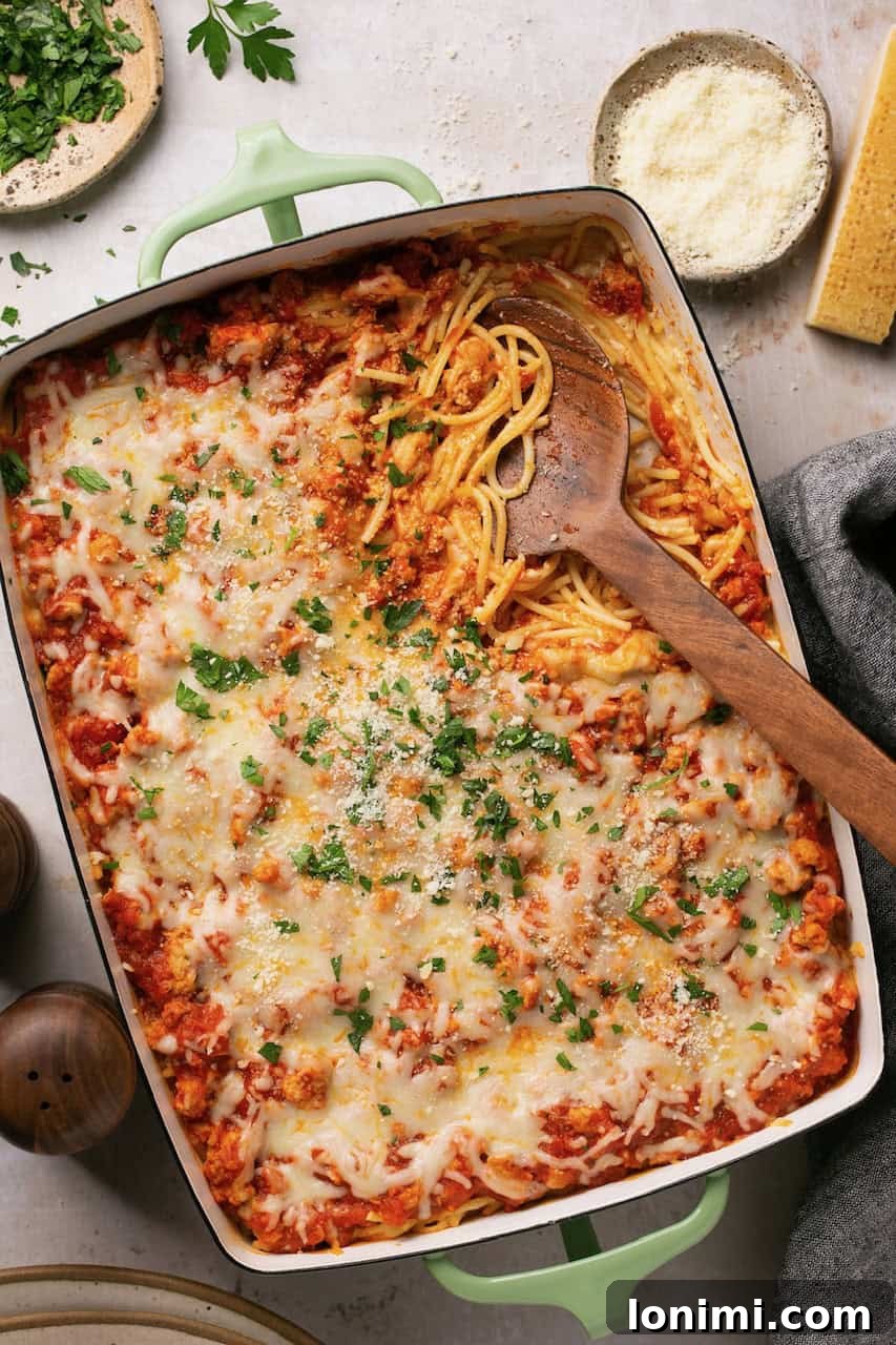 TikTok spaghetti alfredo in a baking dish with a wooden spoon resting on the side, showcasing the cheesy, baked goodness.