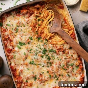 Gluten-free spaghetti alfredo bake in a casserole dish with a serving spoon taking a scoop out