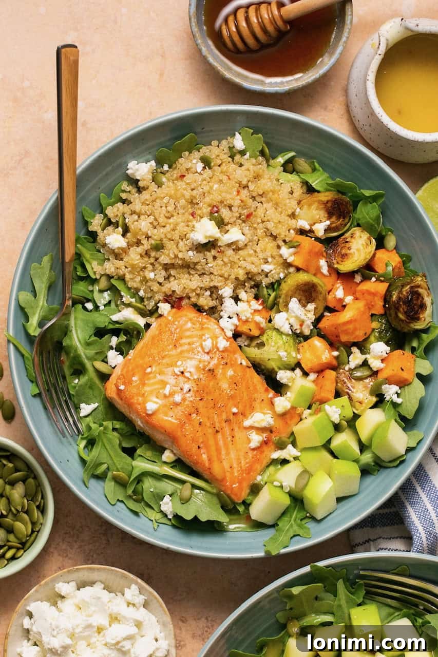 salmon quinoa bowl with brussels sprouts, sweet potatoes, arugula, apples and honey lime vinaigrette with a fork