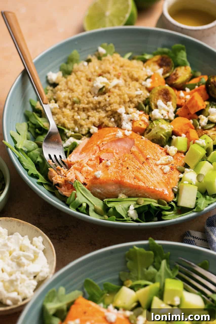 an up close photo of a piece of salmon resting on top of quinoa, arugula and other veggies. 