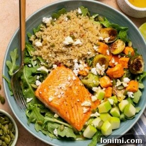 salmon quinoa bowl with brussels sprouts, sweet potatoes, arugula, apples and honey lime vinaigrette with a fork