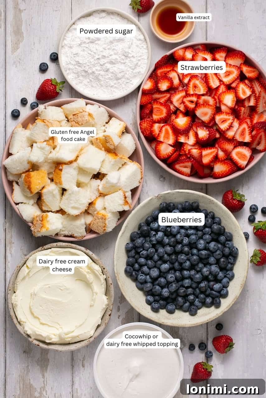 Heavenly Gluten-Free Strawberry Angel Food Trifle 3 Fresh ingredients for a gluten-free berry angel food cake trifle, including strawberries, blueberries, cream cheese, and whipped topping, arranged on a white surface.
