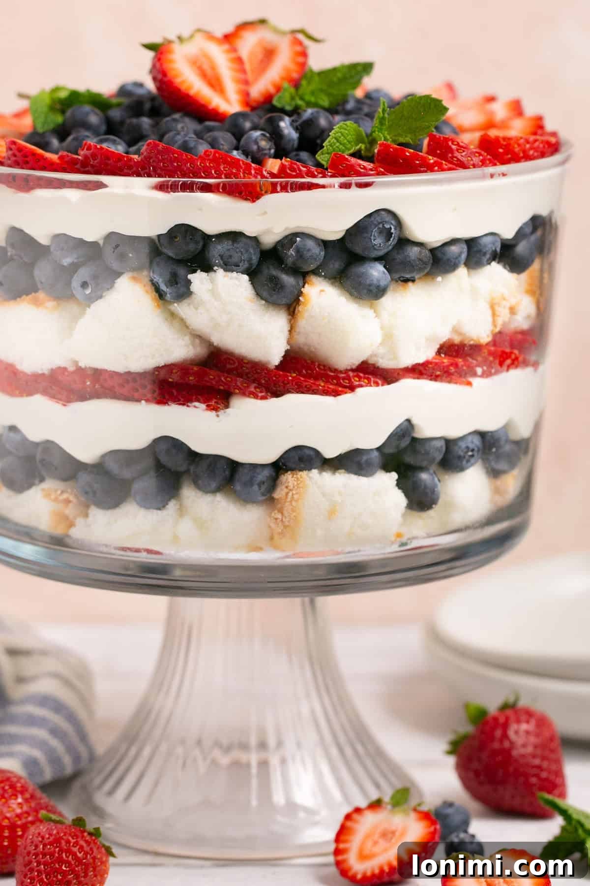 Heavenly Gluten-Free Strawberry Angel Food Trifle 7 A stunning gluten-free berry angel food cake trifle, overflowing with fresh blueberries and strawberries, and garnished with mint, in a large glass bowl.