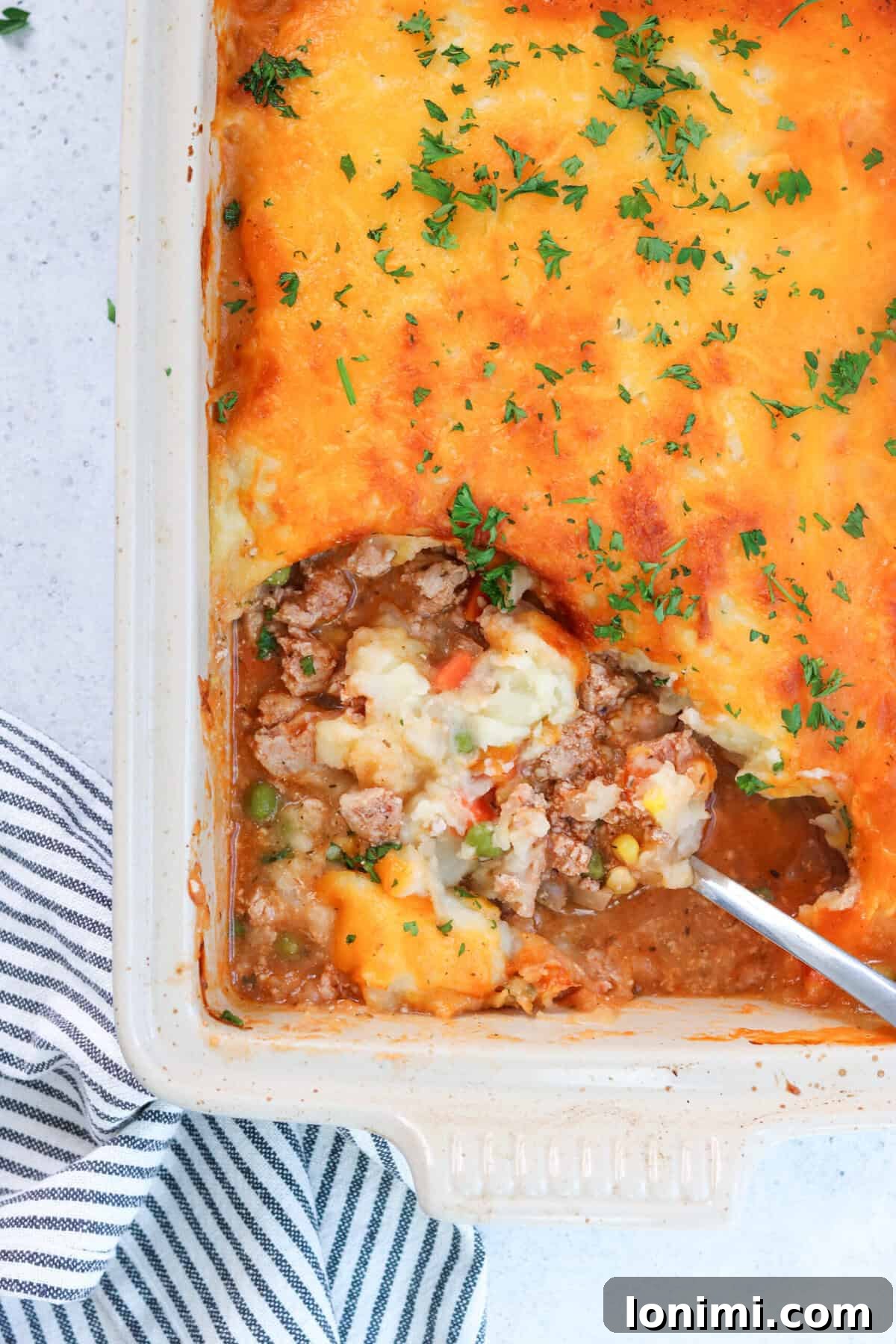 shepherd's pie in a casserole dish with a scoop being taken out
