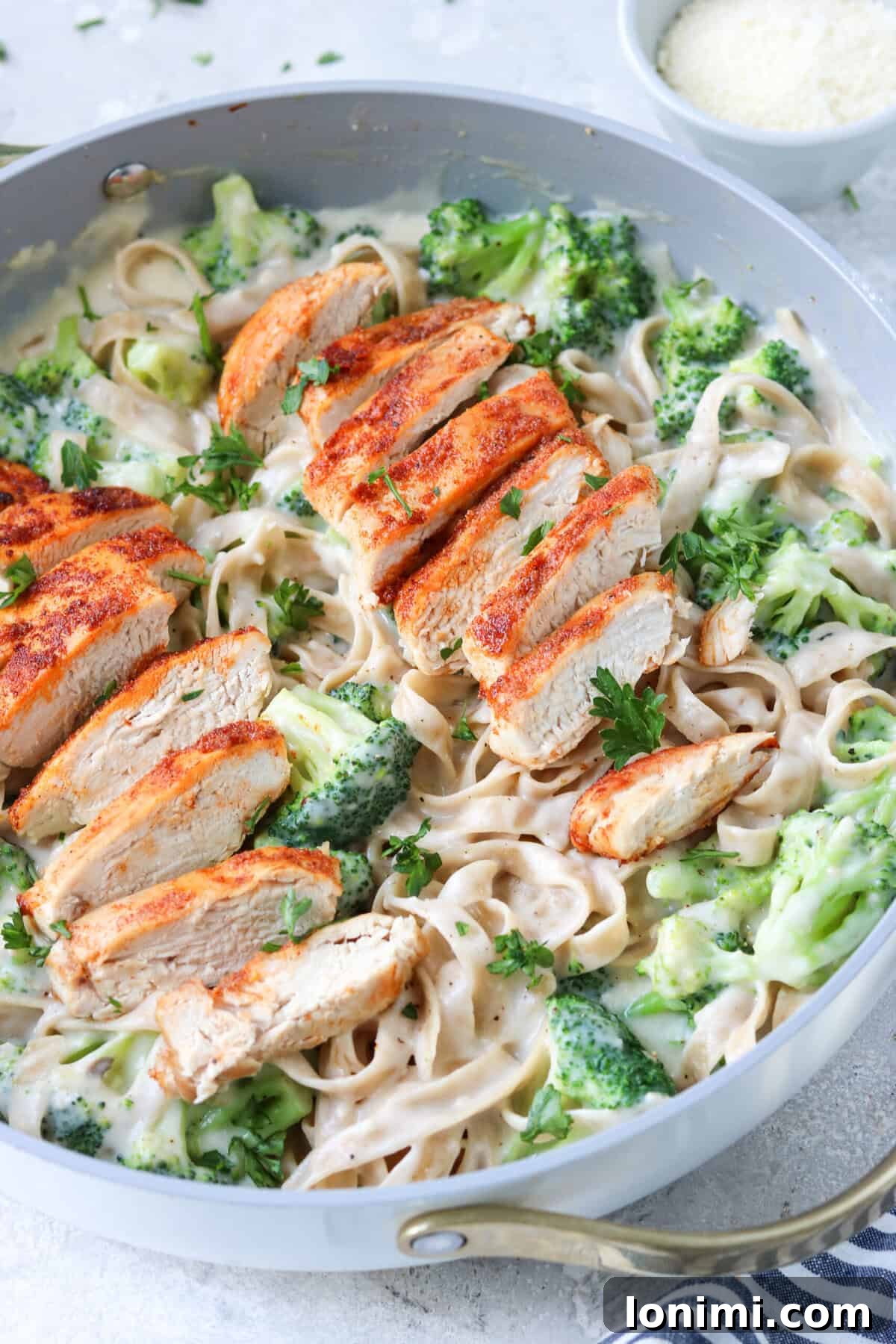 chicken and broccoli with alfredo sauce and gluten free tagliatelle pasta in a skillet