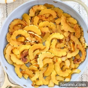 Sautéed delicata squash in a skillet, ready to serve, surrounded by seasonal decor.