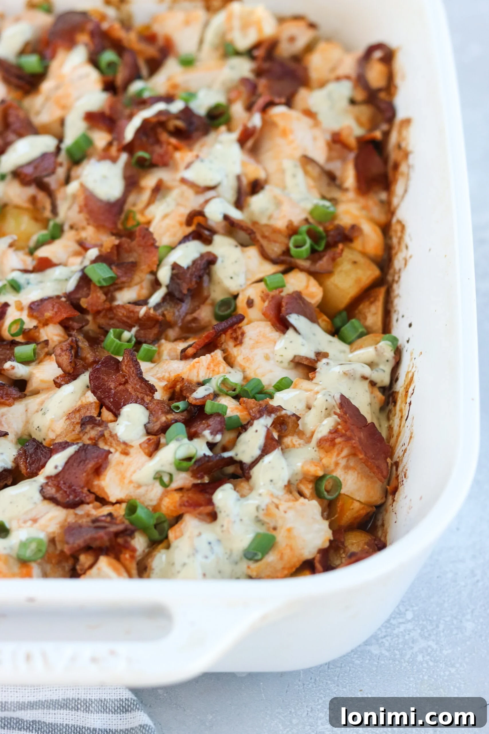 Whole30 Loaded Potato and Buffalo Chicken Casserole in a baking dish, garnished with green onions and ranch