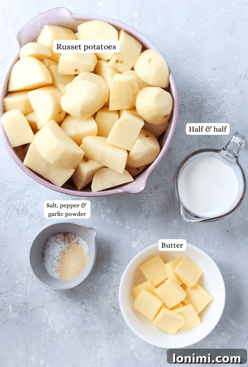 Ingredients for gluten-free mashed potatoes arranged in nesting bowls: russet potatoes, butter, half and half, salt, pepper, garlic powder, and chives.