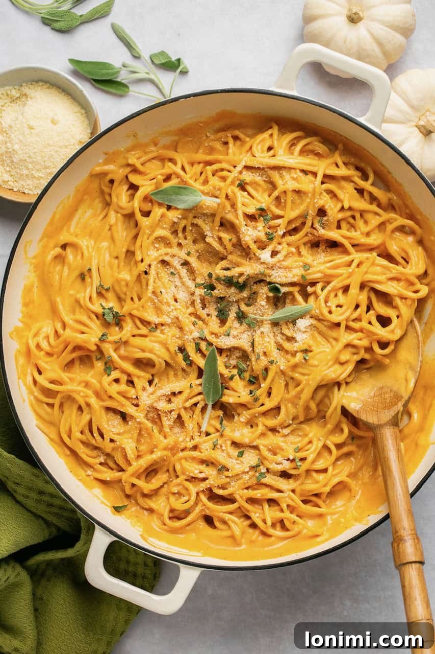 Velvety Pumpkin Pasta 7 Pumpkin pasta sauce mixed with spaghetti in a large pan, garnished with fresh sage leaves and ready to be served.