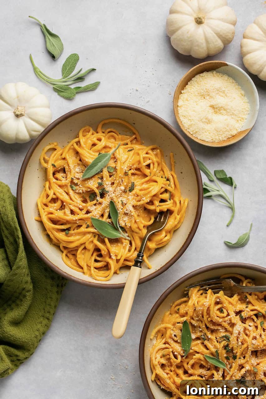 Velvety Pumpkin Pasta 8 Two serving bowls of pumpkin pasta, generously topped with fresh sage leaves, showcasing the vibrant orange sauce.