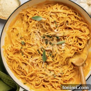 Velvety Pumpkin Pasta 9 Pumpkin pasta sauce with spaghetti in a pan with a wooden spoon topped with sage