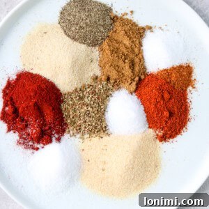 Close-up of chicken taco seasoning spices individually portioned out on a white plate, showcasing their vibrant colors and textures.