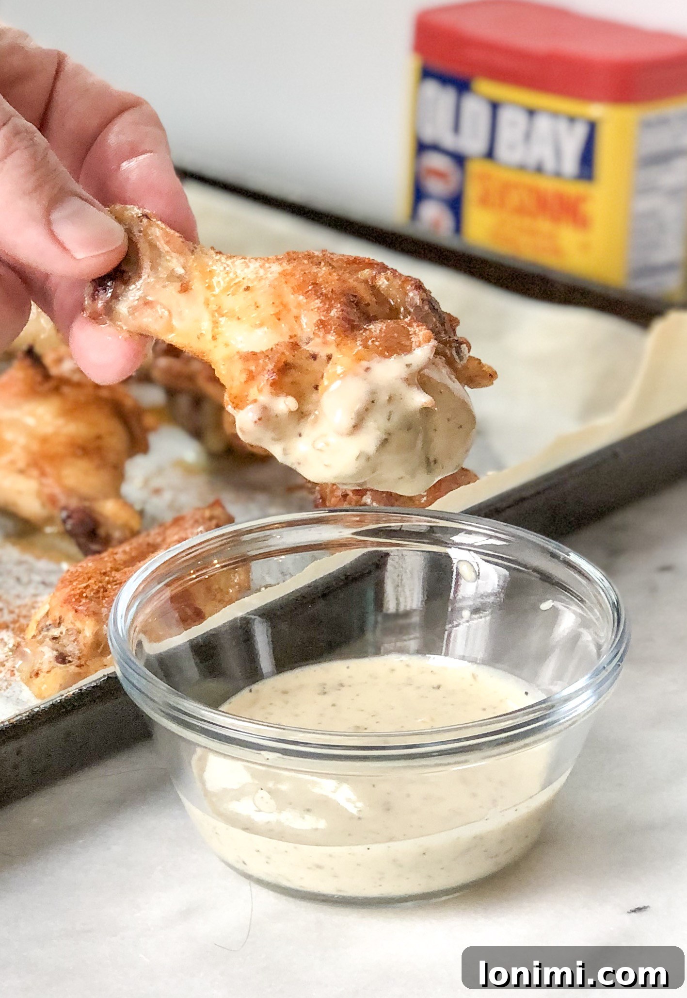 Paleo Whole30 Old Bay Wings 3 Crispy Old Bay Wing being dipped in ranch dressing