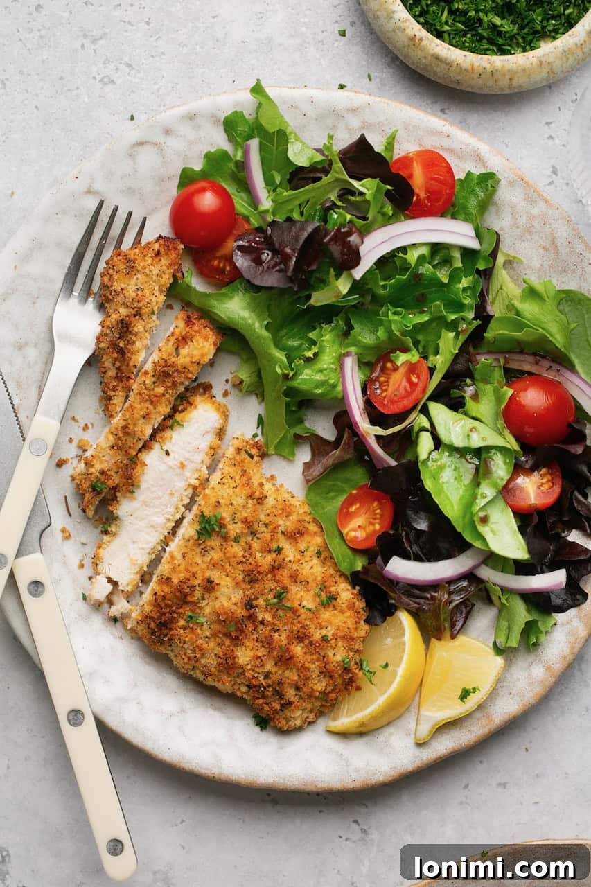 crispy chicken cutlets sliced next to a side salad