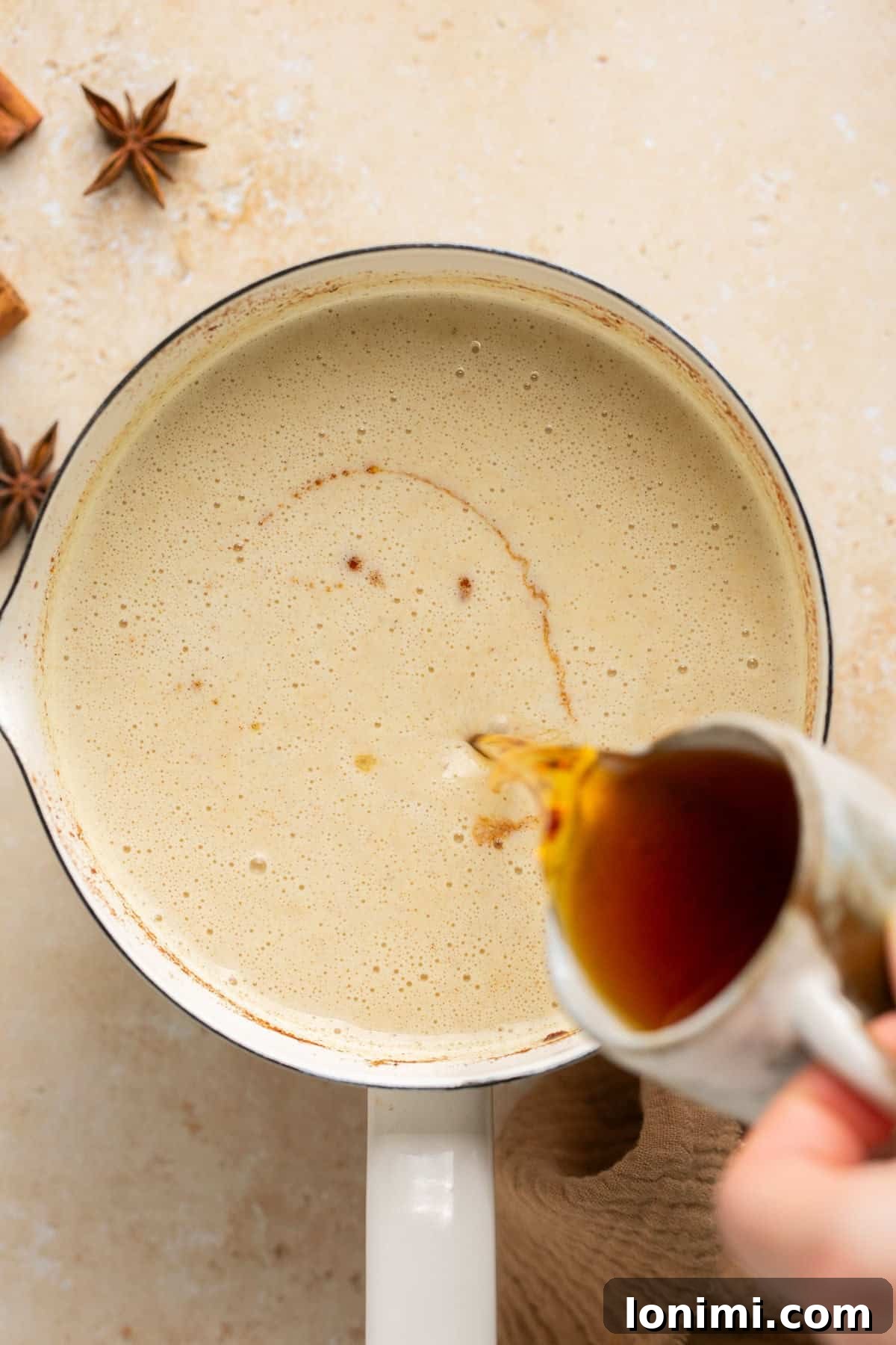 A stream of Flor de Caña dark rum being poured into a pot of simmered eggnog mixture, adding the final touch.