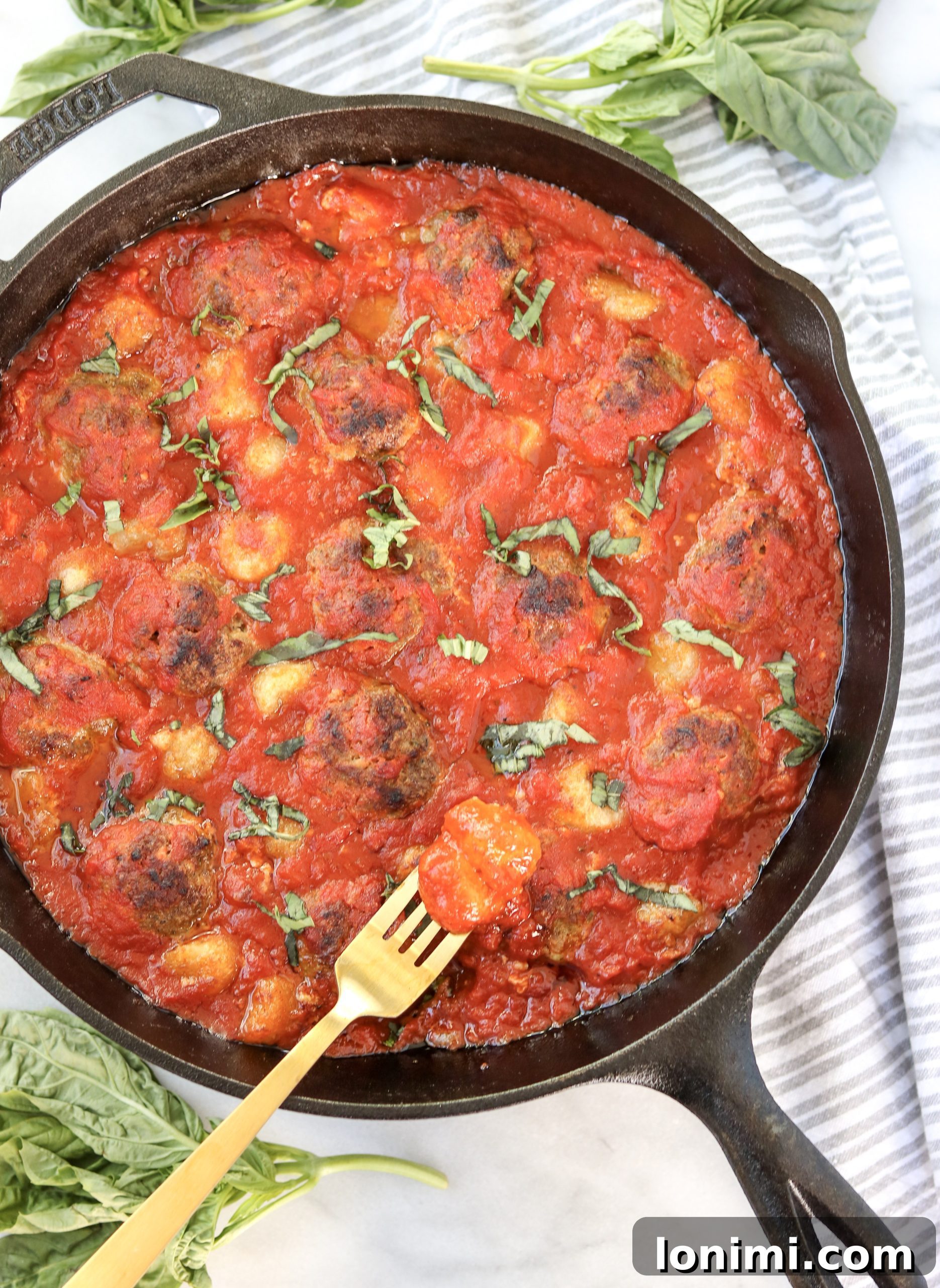 A serving of the Skillet Pesto Meatball and Cauliflower Gnocchi Bake in a bowl, showing the browned meatballs, tender gnocchi, and rich marinara sauce.