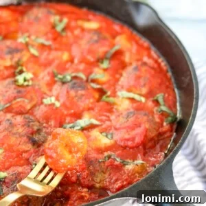 The Skillet Pesto Meatball & Gnocchi Bake presented in a large skillet, topped with fresh basil.