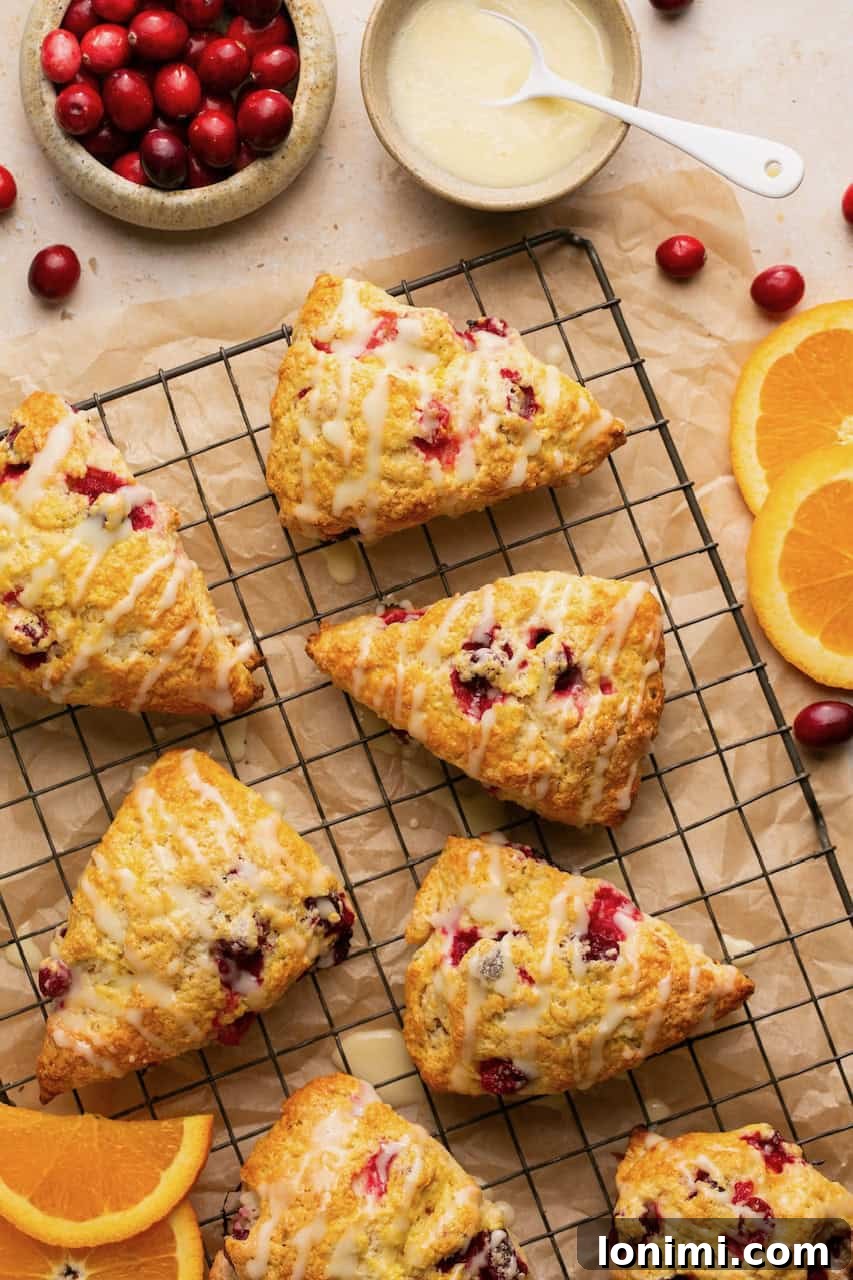Freshly baked gluten-free orange cranberry scones cooling on a rack, ready to be glazed.