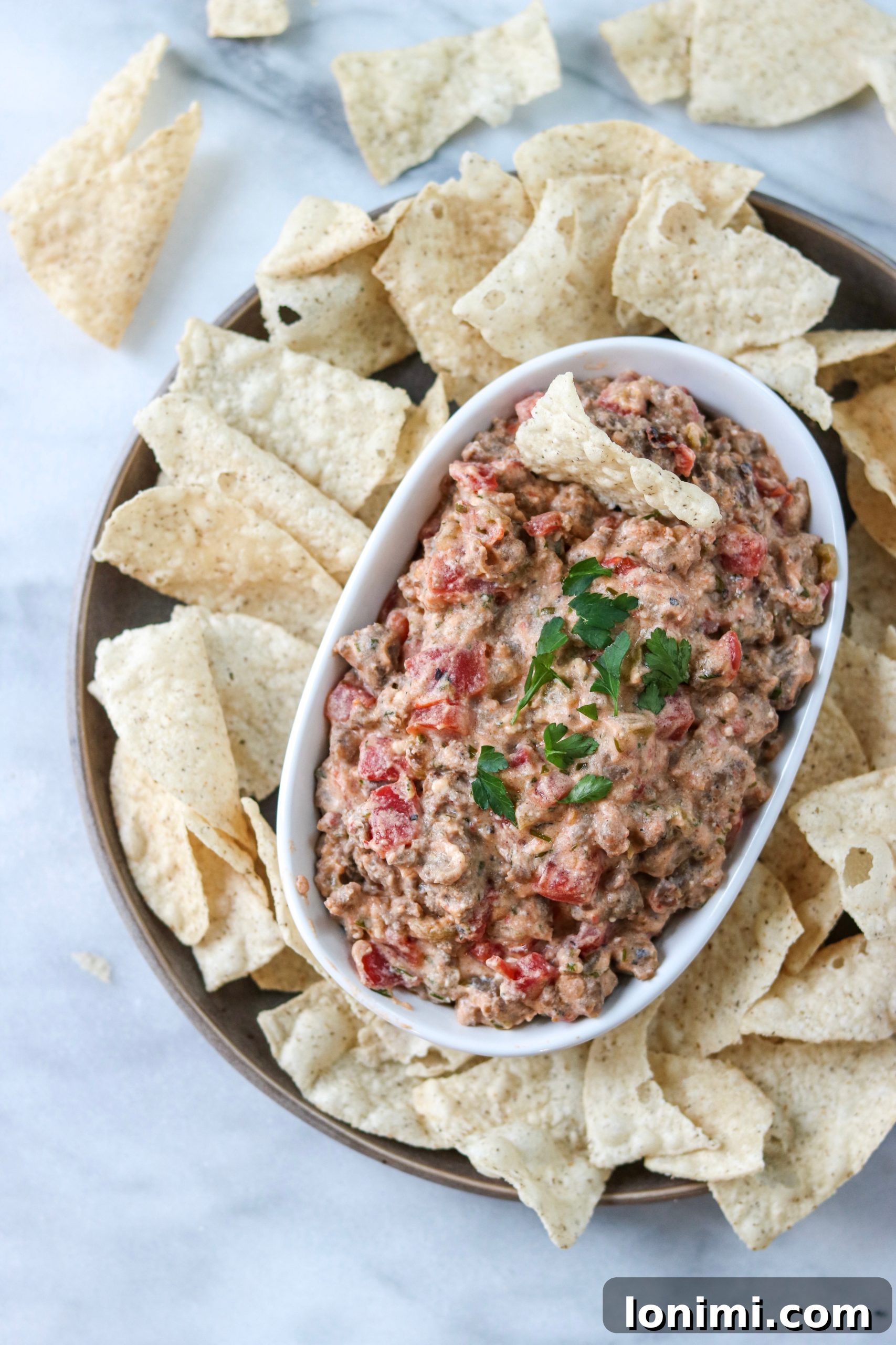Creamy Dairy-Free Sausage Dip with tortilla chips and fresh vegetables on a rustic serving board, perfect for game day or any party.