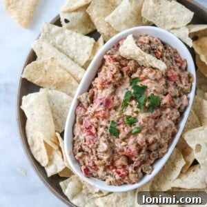 Close-up shot of the finished Dairy Free Sausage Dip in a baking dish, with a scoop taken out.