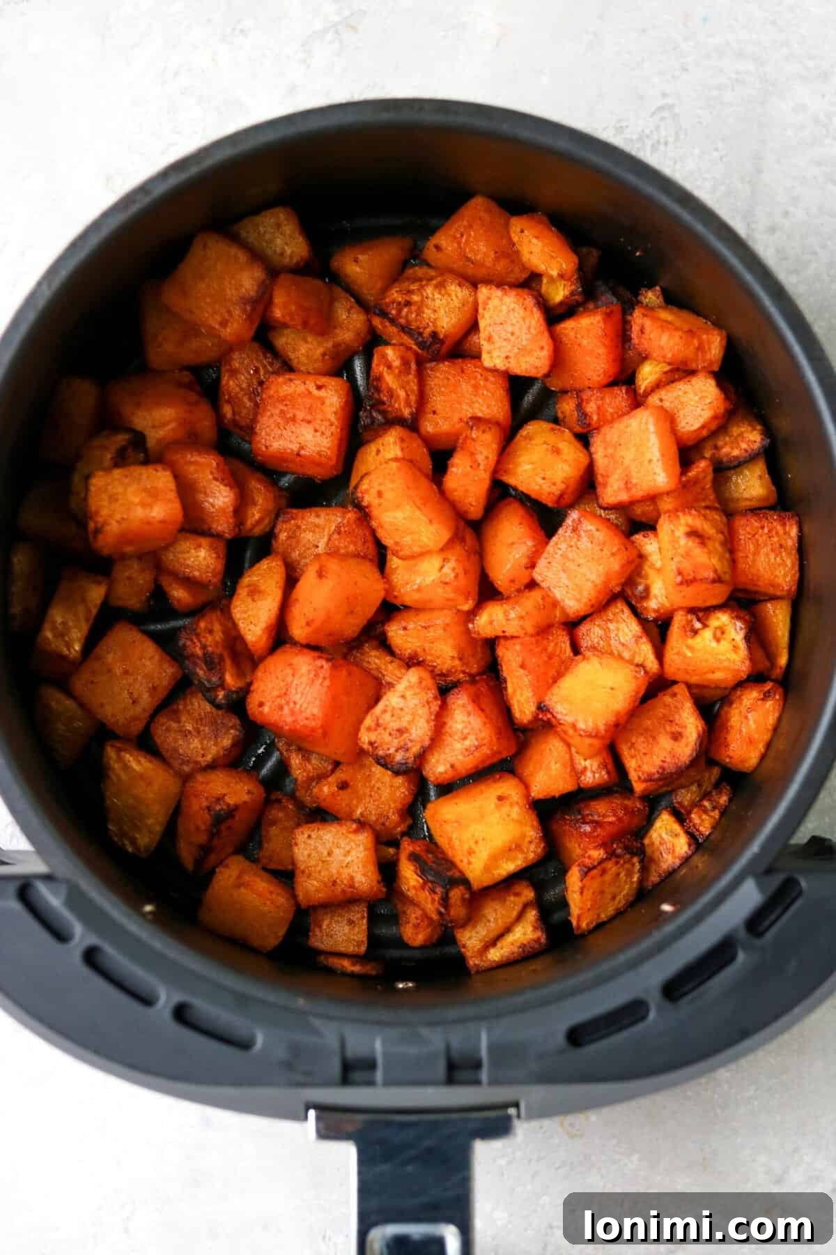 cooked butternut squash in an air fryer basket