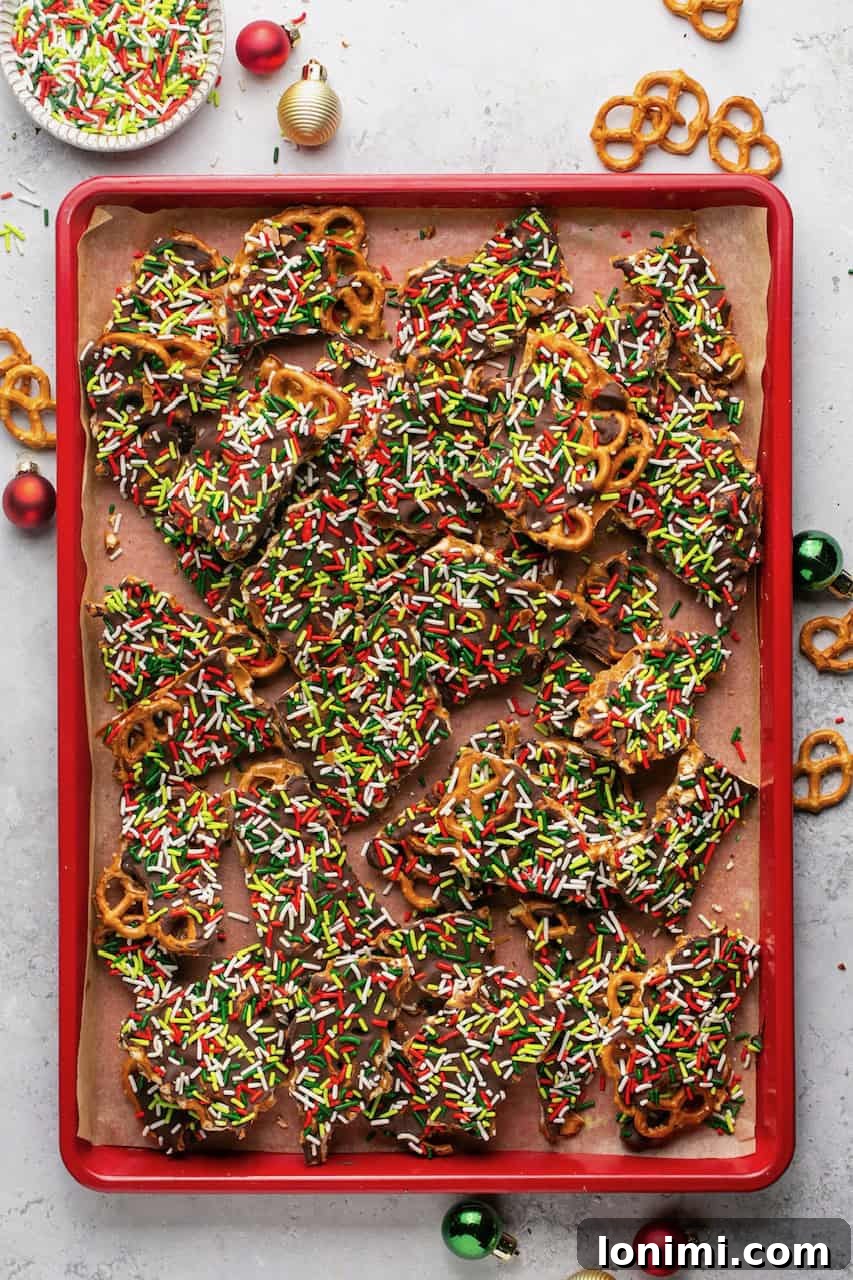 Addictive Gluten-Free Holiday Pretzel Bark 7 A vibrant close-up of gluten-free pretzel Christmas crack, perfectly set and broken into rustic pieces, displayed on a cheerful red baking sheet, highlighting its textures.