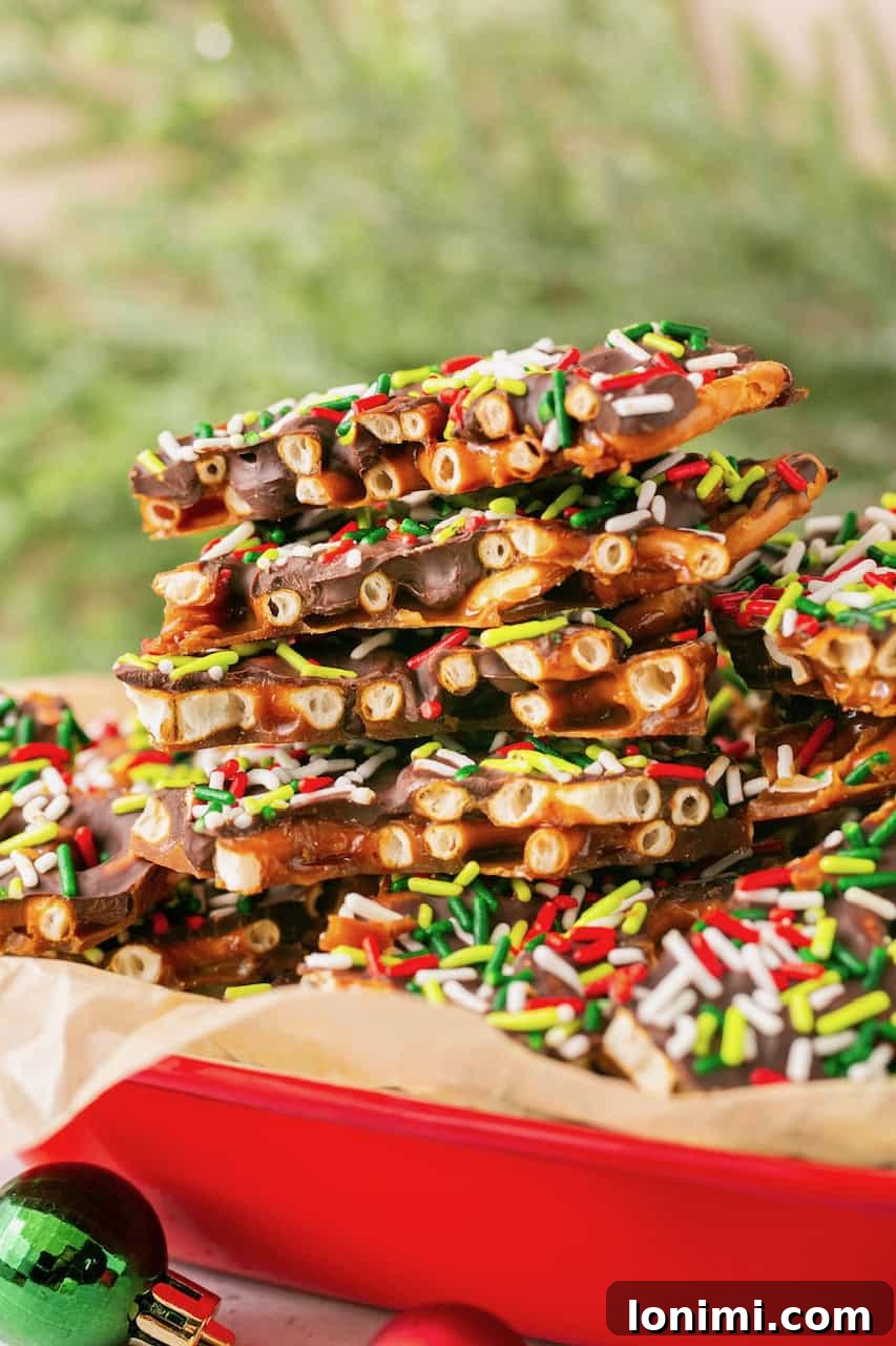 Addictive Gluten-Free Holiday Pretzel Bark 8 A tall stack of gluten-free pretzel Christmas crack pieces, showcasing the multi-layered texture, neatly arranged on parchment paper.