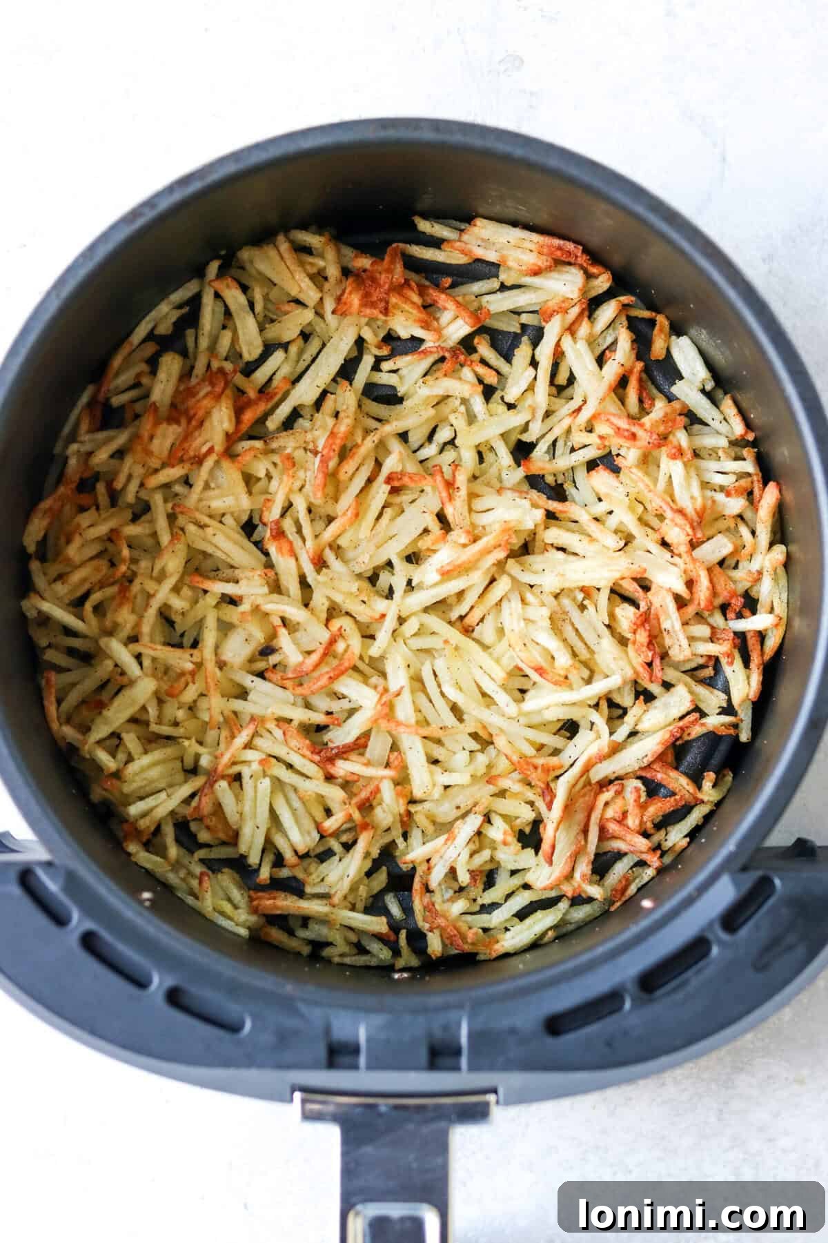 air fryer frozen hash browns in an air fryer basket