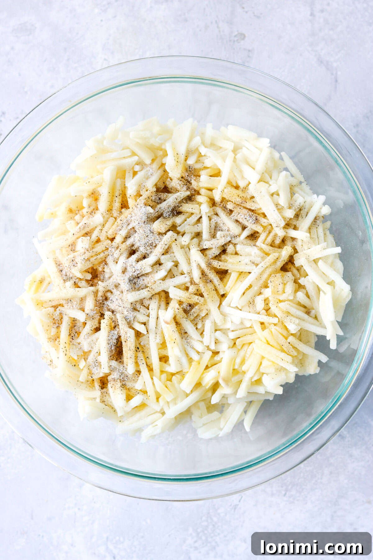 frozen hash browns in a bowl with oil and spices