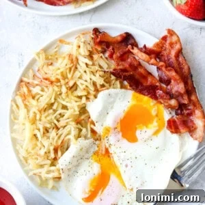 air fryer frozen hash browns on a plate with eggs and bacon