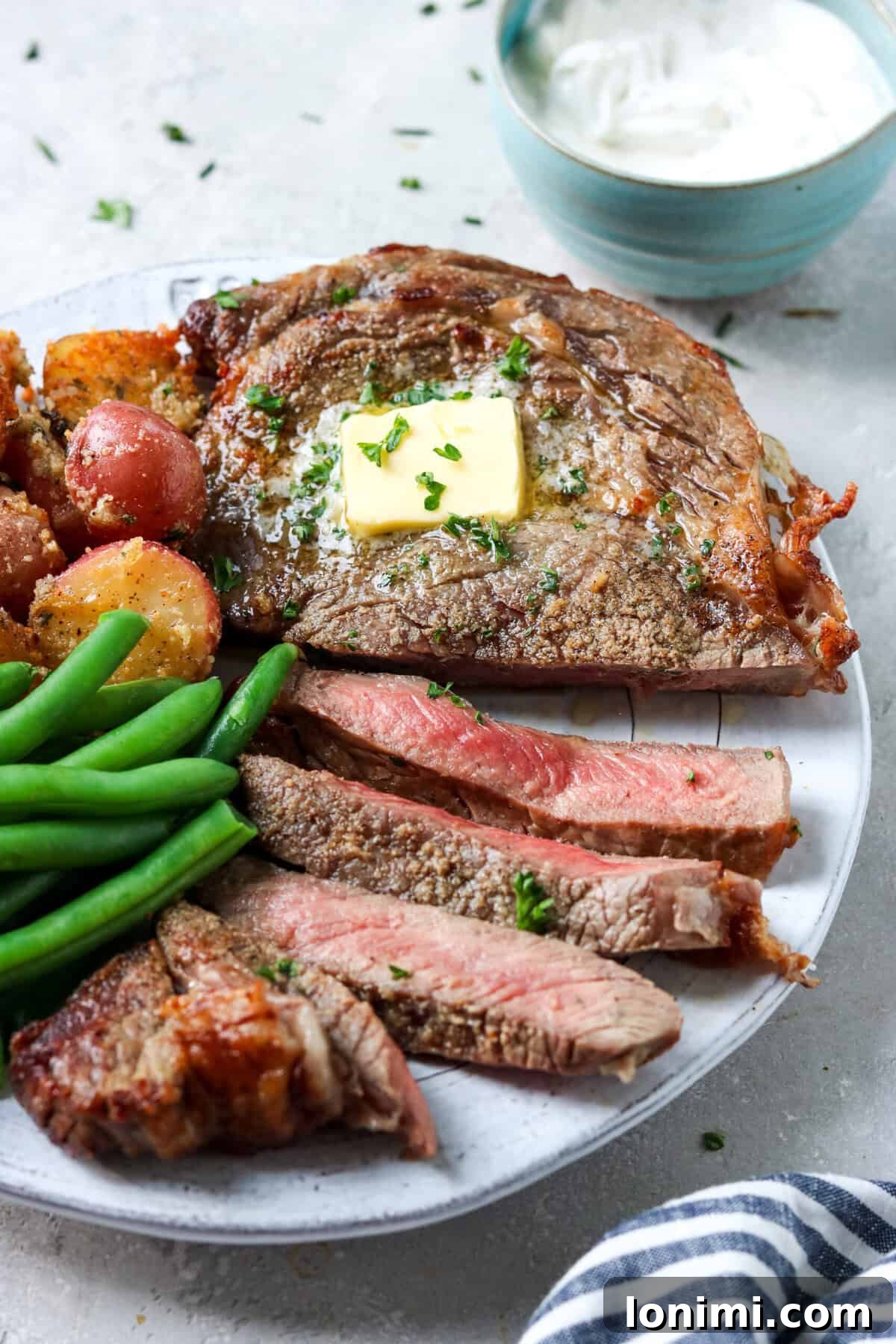 ribeye steak on a plate with green beans and potatoes