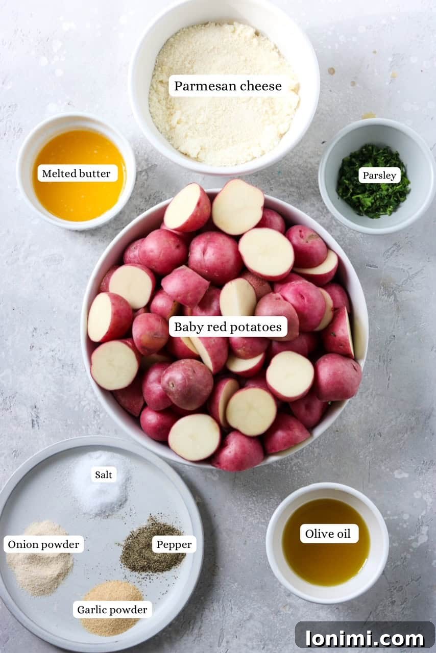 A selection of fresh ingredients laid out on a surface, including baby potatoes, grated parmesan cheese, fresh parsley, butter, olive oil, and various spices, ready for making crispy parmesan potatoes.