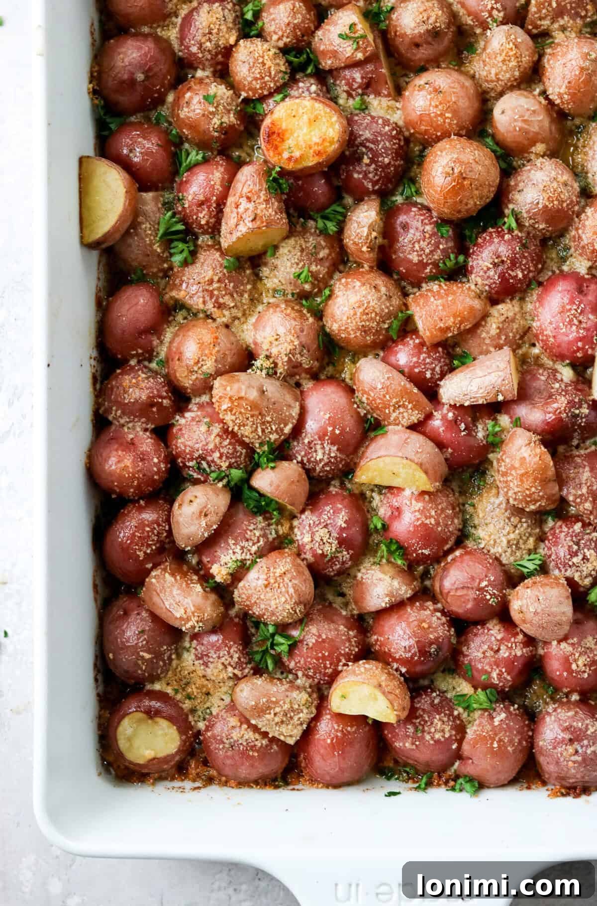 A baking dish filled with freshly roasted crispy parmesan potatoes, golden brown and glistening, straight from the oven.