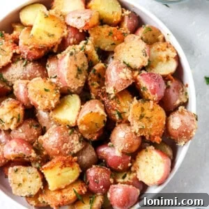 crispy parmesan potatoes in a while bowl with a side of sour cream