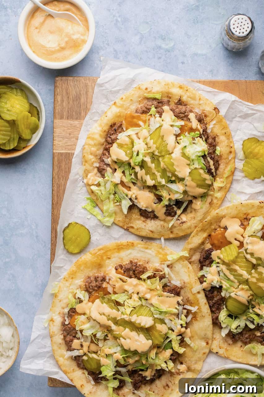 Smash burger Big Mac tacos on parchment paper, topped with shredded lettuce, pickles, melted cheese, and creamy Big Mac sauce. A perfect blend of burger and taco.
